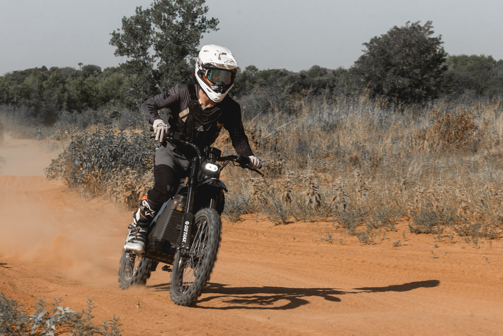 A person riding the GOTRAX Everest electric dirt bike with deep-tooth off-road tires and a 53 mph max speed.