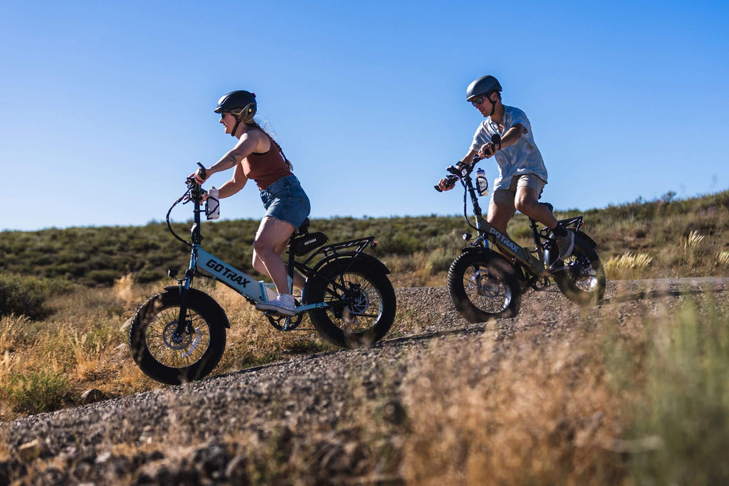 Two people riding the GOTRAX F3 Fat Tire Folding Electric Bike on an outdoor trail.