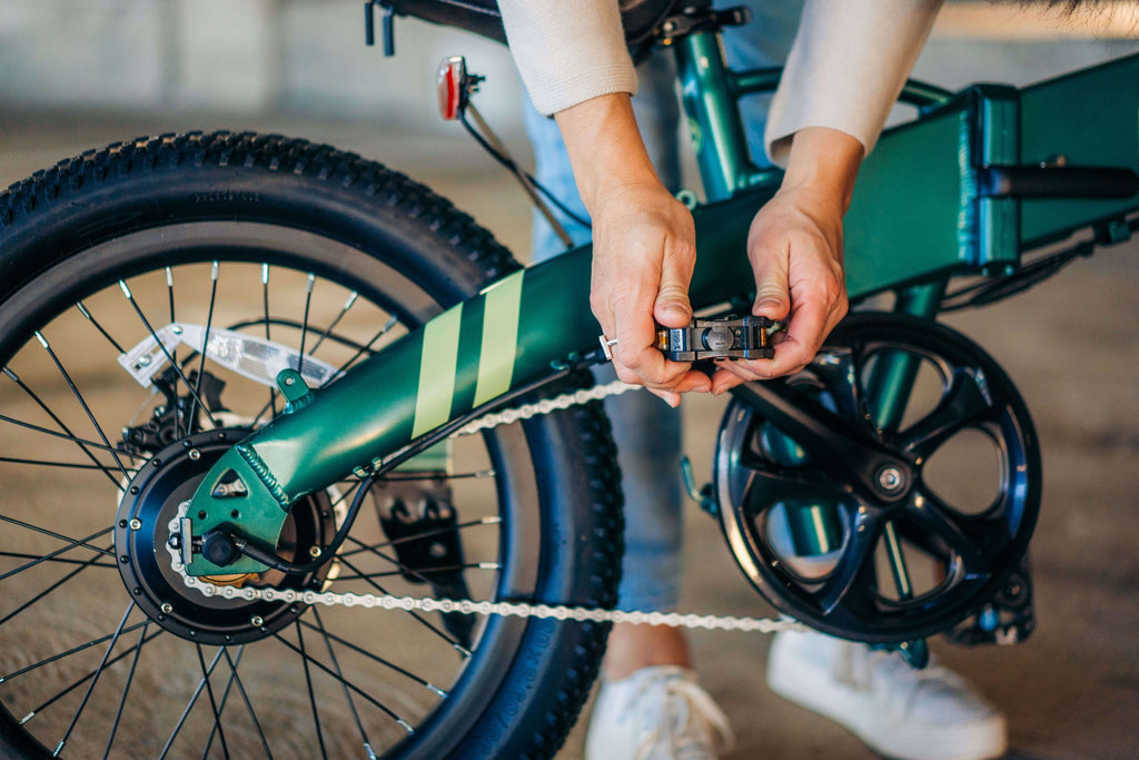 A woman folding the pedals of the GOTRAX F1 Folding Electric Bike.