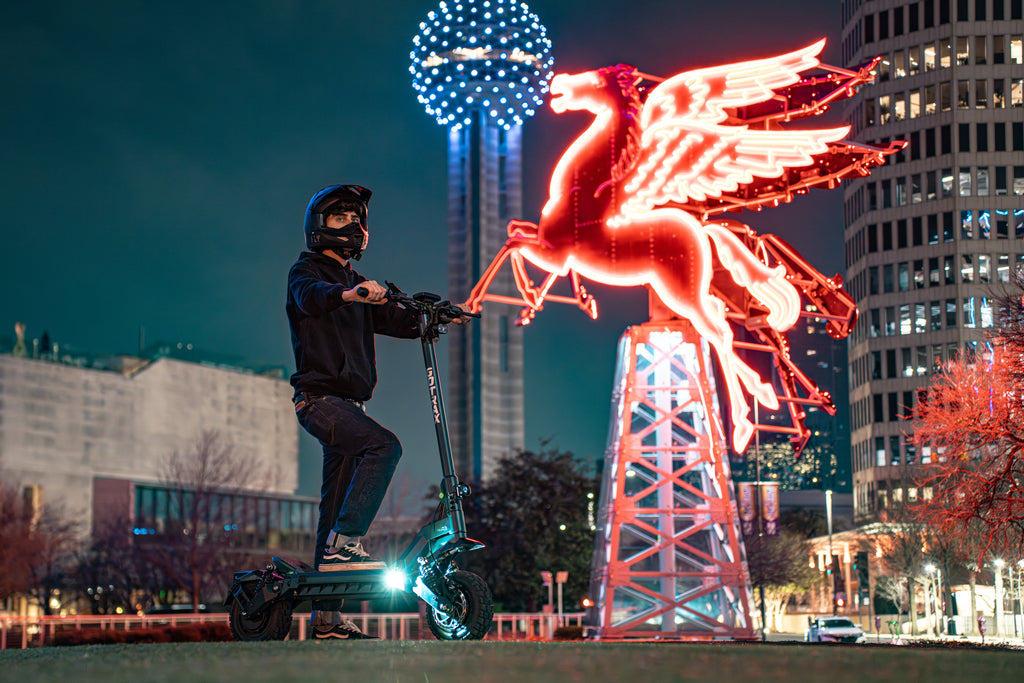 A man standing outside with the GOTRAX GX3 Dual Motor Electric Scooter at night.
