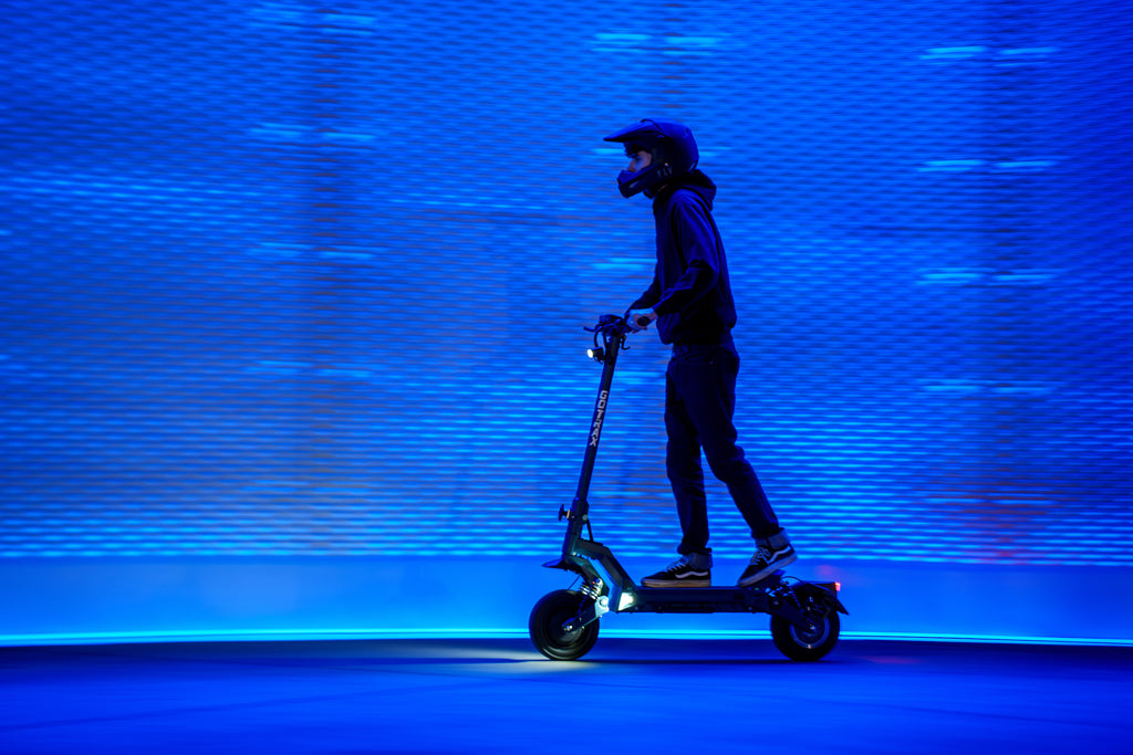 A man riding the GOTRAX GX3 Dual Motor Electric Scooter during nighttime.